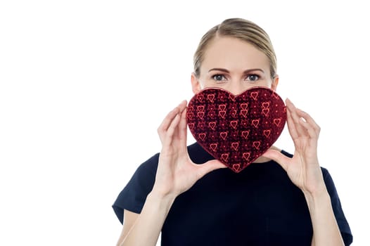 Young woman hiding her face with heart shape gift box
