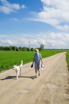 Woman with a dog goes on a country road
