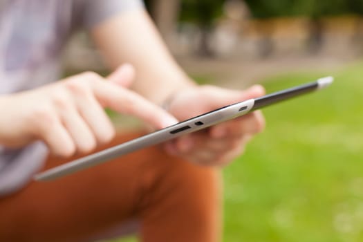Young man read news and communicate on social networks with tablet computer in park