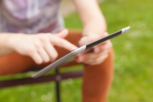 Young man read news and communicate on social networks with tablet computer in park