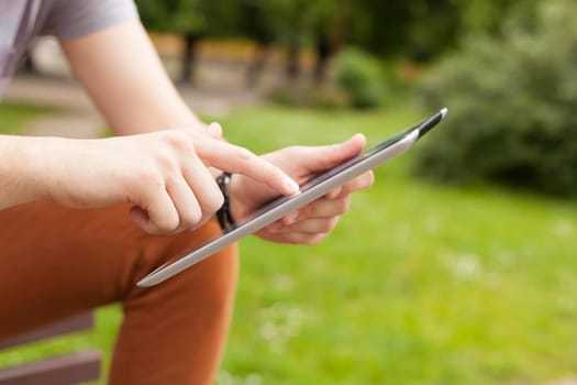 Young man read news and communicate on social networks with tablet computer in park