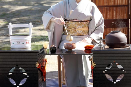 KAGAWA, JAPAN - OCTOBER 25, 2015: Japanese woman in traditional kimono prepares the tea ceremony at garden of the Marugame-castle on October 25, 2015 in Kagawa Japan.