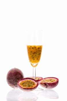 Juicy fruit pulp of purple passion fruit presented in its hard outer rind and in a champagne flute. Sweet sour cocktail and tropical delight. Studio shot over white background and reflective surface.