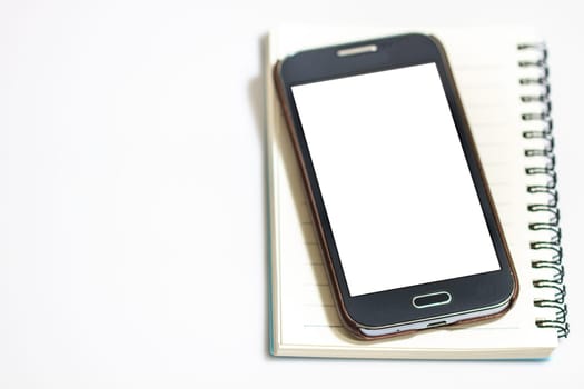 Opened notepad with smart phone on white background