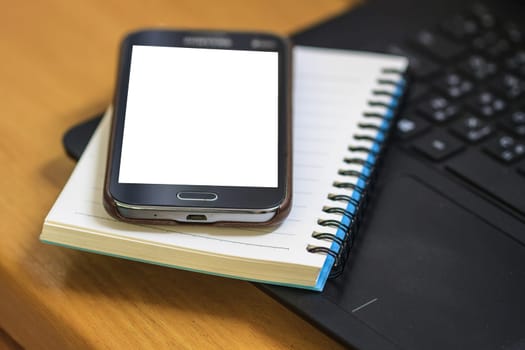 Laptop with book and smartphone on work desk