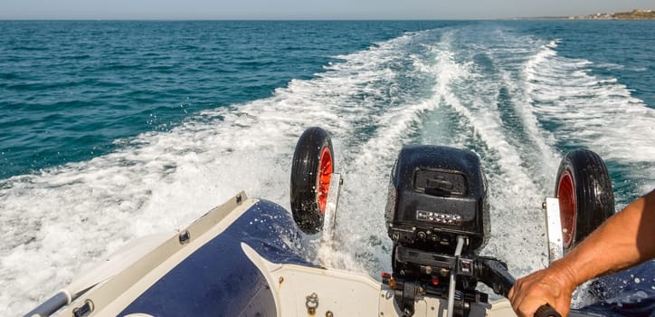 boat running fast leaving a white trail on the blue sea