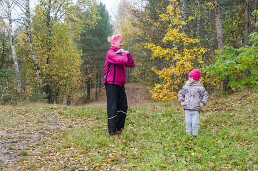 Woman with girl doing aerobics in the autumn park