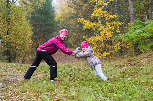 Woman with girl doing aerobics in the autumn park