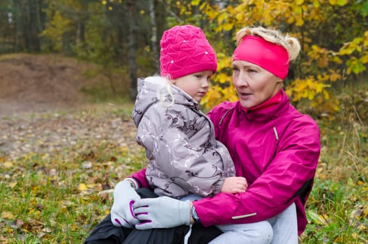 Woman with girl doing aerobics in the autumn park
