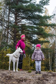 Granny with her granddaughter and a dog walk in autumn Park