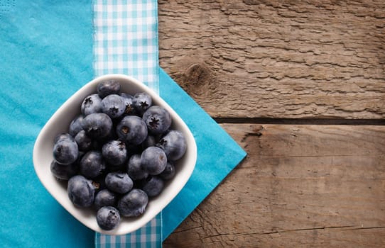 Fresh blueberries in a white bowl on a rustic table
