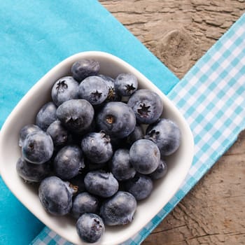 Fresh blueberries in a white bowl on a wooden table
