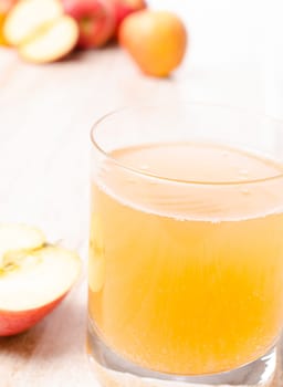 Glass of organic apple juice with fresh apples on a kitchen table