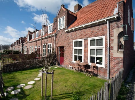 Village street with picturesque houses with small front gardens. The brick houses are located in Zoeterwoude in the Netherlands