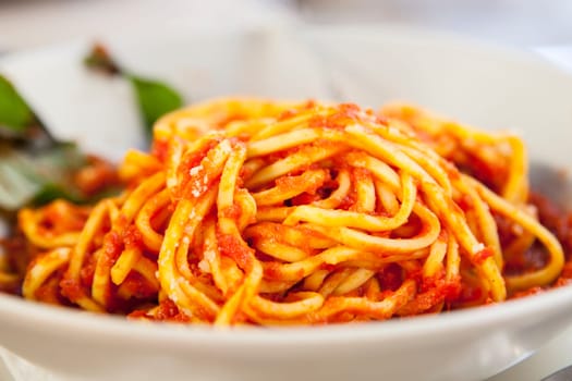 Plate of spaghetti bolognese with basil garnish. Closeup shot with selective focus