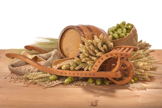 Old barrel with wheelbarrow,wheat,barley,hops and malt against a white background