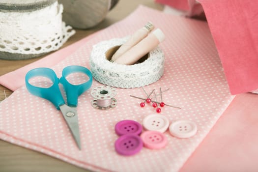 Buttons and sandnails lie on different fabrics with scissors
