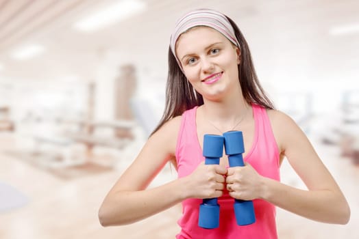 a portrait of pretty sporty girl holding weights
