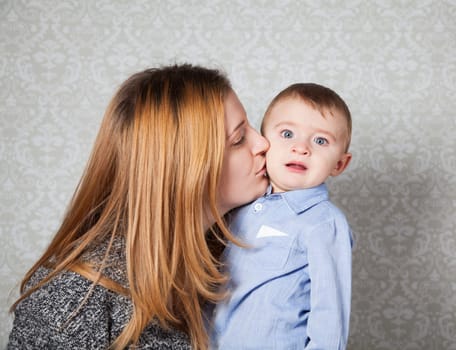 1 year old baby boy in his mother's arms, studio portrait.