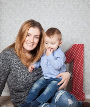 1 year old baby boy in his mother's arms, studio portrait.