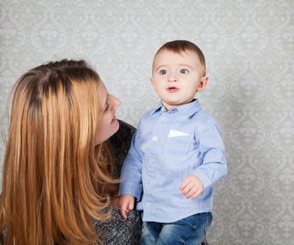 1 year old baby boy in his mother's arms, studio portrait.