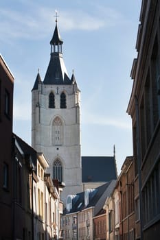 The Church of Our Lady across the river Dijle in Mechelen was founded in 1236. In Dutch language it's called the Onze-Lieve-Vrouwekerk. The sunlight in the street leads to the white Brabant gothic style church. It’s one of the touristic attractions in Mechelen.