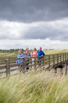 Portrait of a family of four walking across a bridge. They are wearing casual clothing and enjoying their leisure time together.