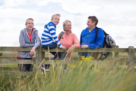 Happy Family of Four on a bridge. They are wearing casual clothing and looking at the surrounding area.