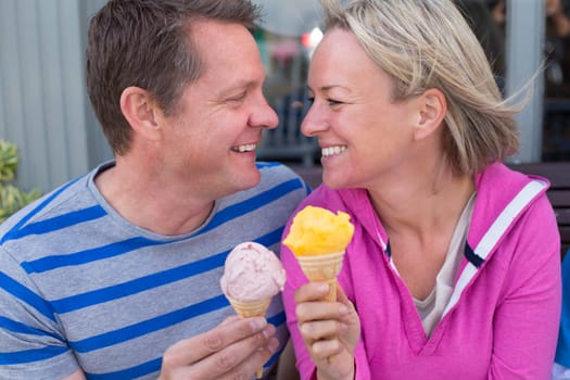 Mature Couple enjoying ice cream together. They are wearing casual clothing and looking into each others eyes.
