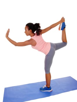 A young African American girl standing on a yoga mat, doing stretching, .in blue tights, isolated for white background..