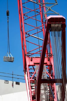 Red crane lifting construction materials