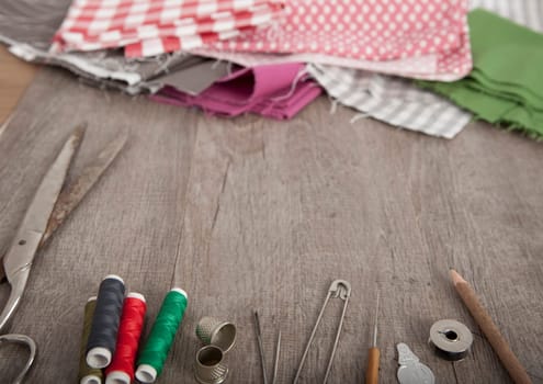 colorful fabrics and accessories for cutting lie on a wooden ground