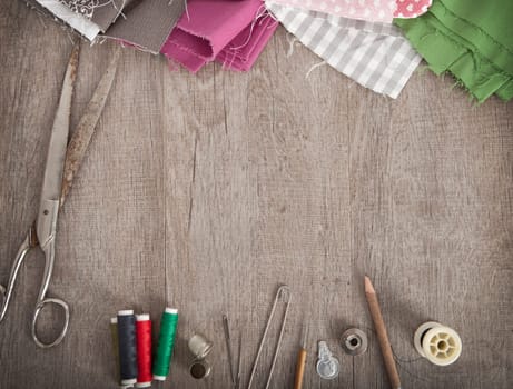 colorful fabrics and accessories for cutting lie on a wooden ground