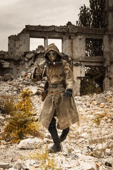 Post apocalypse. Sole survivor in tatters and gas mask on the ruins of the destroyed city