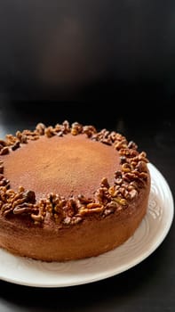 Chocolate cake decorated with walnut on white plate, black background. High quality photo