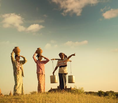 Group of Asian Burmese traditional farmers carrying clay pots on head going back home, Bagan, Myanmar