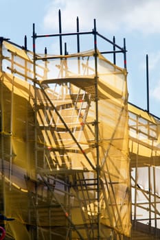 Scaffolding with yellow protection net. It looks like a castle.