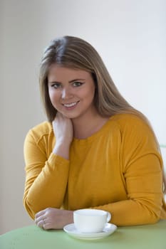 Portrait of a young woman enjoying a cup of tea. She is smiling at the camera.