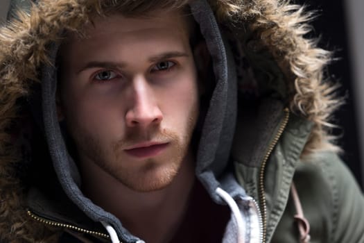 Close up portrait of a young man posing with his hood up.