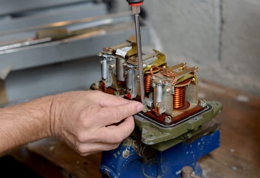 Electrician repairs a regulator of car in his workshop
