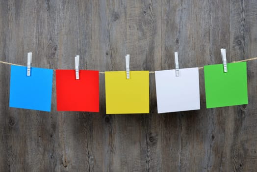 5 colored post it hanging on a clothesline.