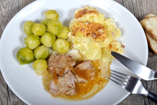 meat platter with gratin potatoes and Brussel sprouts on the wood table