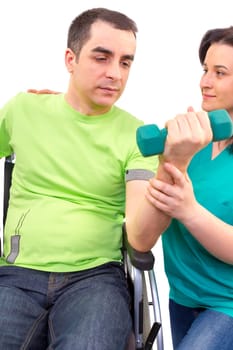 Physical therapist works with patient in lifting hands weights. young adult in wheelchair.