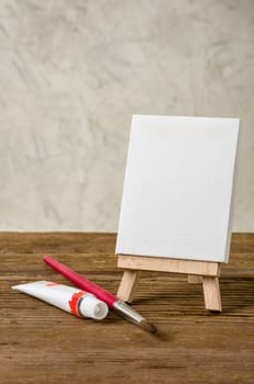 Easel with blank canvas,paint tube and brush