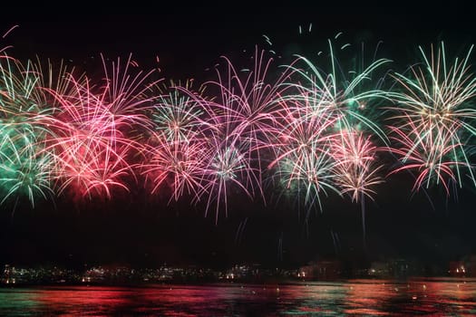 colorful fireworks reflect on sea water