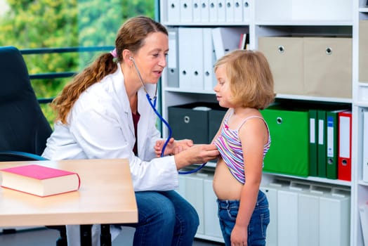 female pediatrician in white lab coat examined little girl