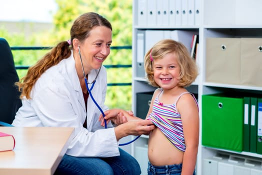 female pediatrician in white lab coat examined little girl
