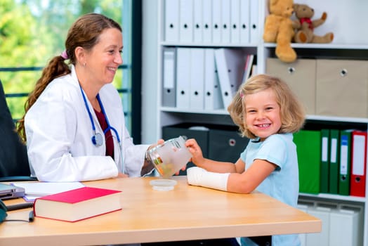 female pediatrician in white lab coat has candys for a little girl