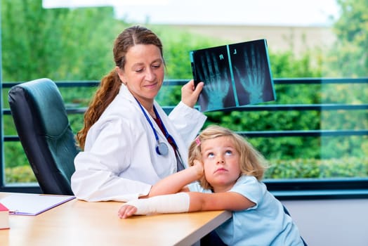 female pediatrician in white lab coat examined little girl