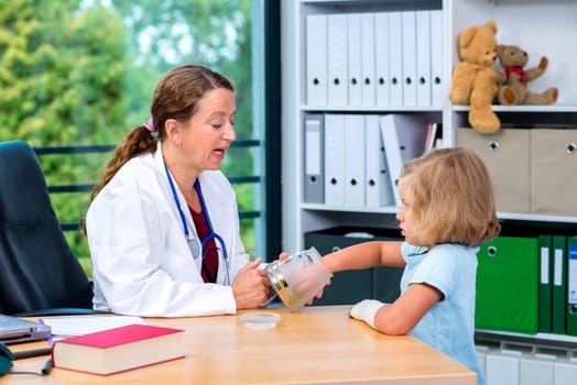 female pediatrician in white lab coat has candys for a little girl